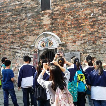学生正在参观碉楼，欣赏其建筑特征，了解其历史背景及所反映的文化特色。