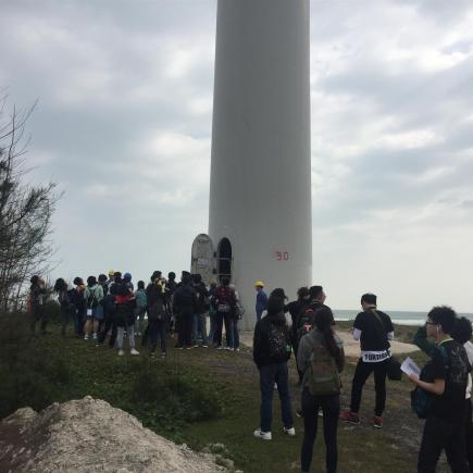 学生在参观华能风电厂的风力发电机。