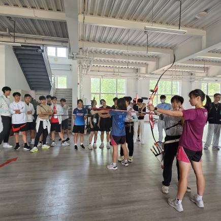 學生在青島市體育運動學校體驗射箭活動，在當地學生指導下，他們躍躍欲試。